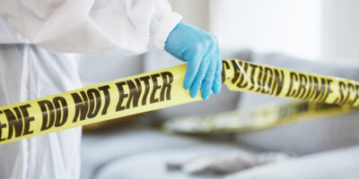 Forensics, crime scene and tape with person in living room for investigation, research and safety. .